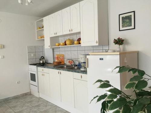 a kitchen with white cabinets and a white refrigerator at Frankie Holiday Apartment II. in Balatongyörök
