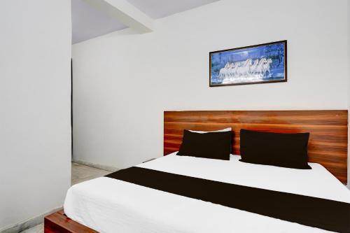 a bedroom with a large bed with a wooden headboard at Hotel O Mayur Deluxe in New Delhi