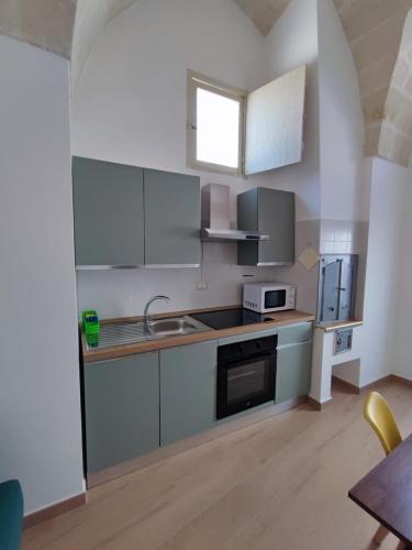 a kitchen with gray cabinets and a sink and a microwave at Appartamento al Bommino in Massafra