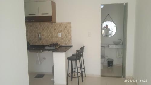 a kitchen with a counter and stools and a mirror at Kitnet Mobiliada in Vitória da Conquista