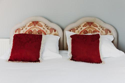 two pillows on a bed with red pillows at Little Orchard - Cowes in Isle of Wight