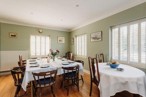 a dining room with a table with white tablecloths at Little Orchard - Cowes in Isle of Wight
