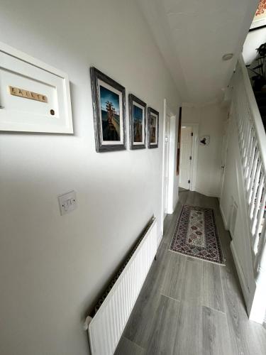 a hallway with white walls and a staircase with pictures on the wall at Bright & Cozy Home in Knocknacarra in Galway