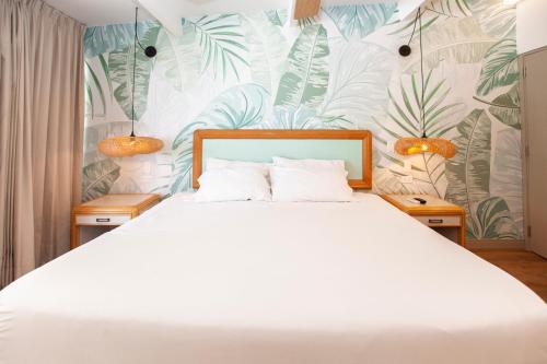 a bedroom with a white bed and tropical wallpaper at Hotel Cocoplum Beach in San Andrés