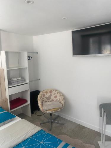 - une chambre avec une chaise et une télévision murale dans l'établissement habitat la DHUYS, à Montreuil