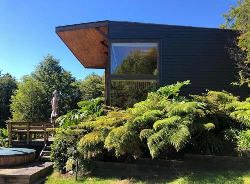 a black house with a window and some bushes at Lofts Magnolias in Puerto Varas