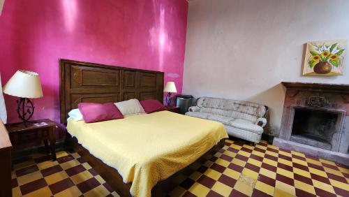 a bedroom with a bed and a chair and a fireplace at Hotel Sautto in San Miguel de Allende
