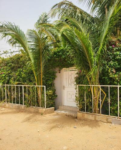 a white gate with two palm trees in front of a garage at Villa Massai avec piscine au cœur de Saly in Sali Nianiaral