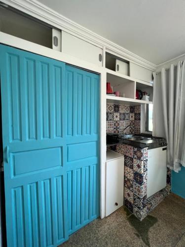 a blue garage door in a room with a desk at Estalagem pé na areia in Arraial do Cabo