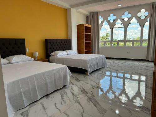 two beds in a bedroom with a marble floor at Hotel Palace in La Concordia