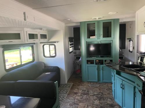 a kitchen with a couch and a tv in a rv at Motel de L'Anse et Camping Rimouski in Rimouski