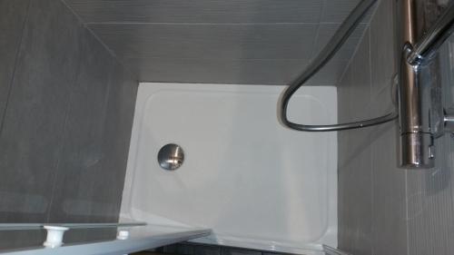 a shower in a bathroom with a white wall at Les Fougères in Métabief