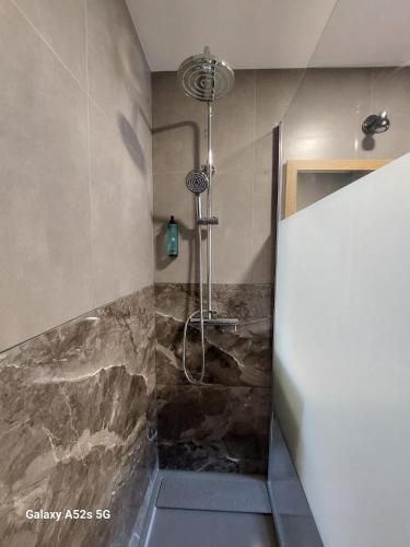 a shower in a bathroom with a stone wall at Highrise Madalenas Apartment in Funchal