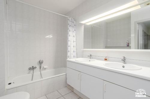 a white bathroom with two sinks and a tub and a mirror at Europan A0502 Esplanade, stijlvol en vlakbij het strand in De Panne