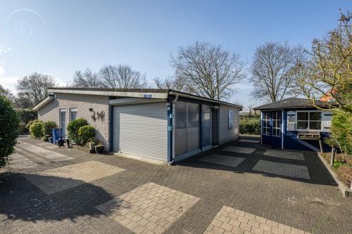 a house with a garage and a building at Summer house on quiet park close to beach in Ouddorp