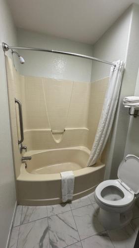 a bathroom with a tub and a toilet and a shower at Sunbridge Inn & Suite Extended Stay in Jourdanton