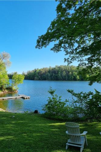 a white bench sitting in the grass near a lake at Lakehouse Inn in Lee