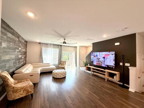 a living room with a couch and a flat screen tv at The Villas The One Villa by RDU Airport with Indoor Heated Pool and Gym in Durham