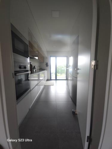 a kitchen with white cabinets and a hallway at Mar à sua janela in Oeiras