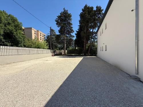 a road with a white wall and a fence at Montelimar Location in Montélimar