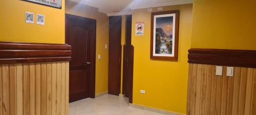a hallway with yellow walls and wooden doors at Hotel California by Chat Noir in Cuenca