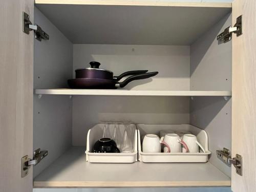 a cupboard with a pot and cups in it at The Shore Cozy Homestay, Heart of KK City Centre in Kota Kinabalu