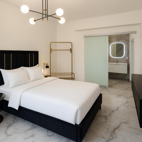 a bedroom with a large white bed and a mirror at Natural Blue Suites-Canal d'Amour Retreat in Sidari