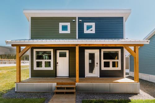 a green house with a porch and a white door at Roamer's Nook in Nordegg