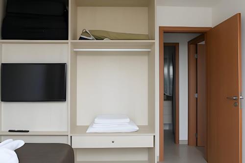 a room with a tv and a shelf with a television at Resort beira-mar Porto Galinhas in Porto De Galinhas