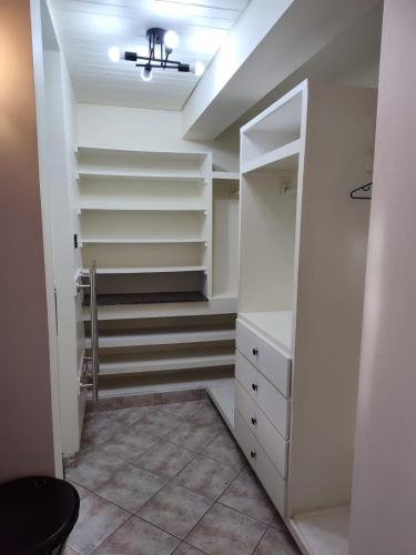 a walk in closet with white shelves and a ceiling at Miss B Apts in Kingstown