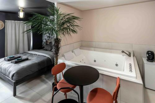 - une chambre avec une baignoire, un lit et une table dans l'établissement Rêve Tropical Balnéo - Votre Pause Enchantée, à Blois