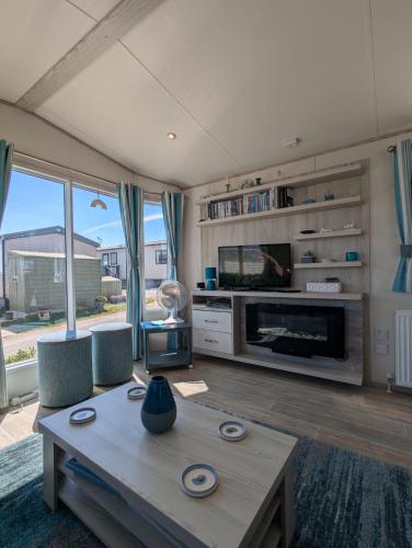 a living room with a table and a fireplace at Beautifully presented beachcomber holiday home sited on the Durdle Door holiday park within a few minutes walk from the path that leads to the famous Durdle Door arch and Lulworth cove in West Lulworth
