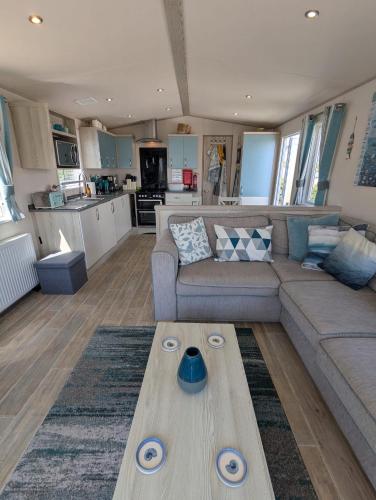 a living room with a couch and a table at Beautifully presented beachcomber holiday home sited on the Durdle Door holiday park within a few minutes walk from the path that leads to the famous Durdle Door arch and Lulworth cove in West Lulworth