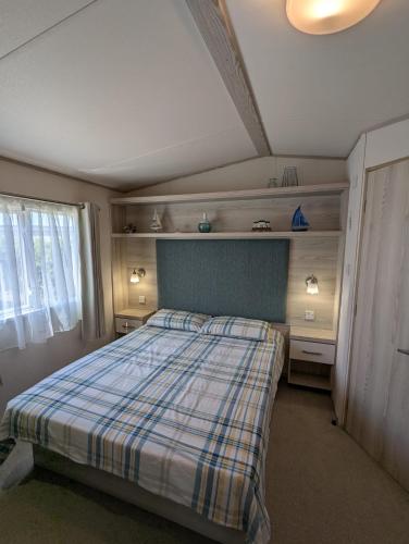 a bedroom with a bed with a plaid blanket at Beautifully presented beachcomber holiday home sited on the Durdle Door holiday park within a few minutes walk from the path that leads to the famous Durdle Door arch and Lulworth cove in West Lulworth