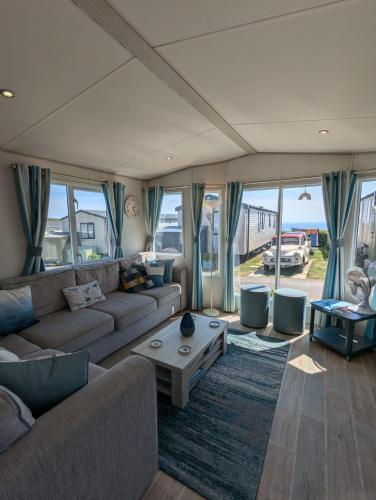 a living room with a couch and a table at Beautifully presented beachcomber holiday home sited on the Durdle Door holiday park within a few minutes walk from the path that leads to the famous Durdle Door arch and Lulworth cove in West Lulworth