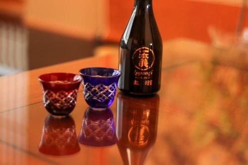 a bottle of wine and two cups on a table at 勝山四季の宿 清流亭 一棟貸で周囲500メートルに民家なし in Katsuyama