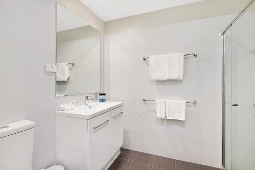 a white bathroom with a sink and a shower at Quest Maitland in Maitland