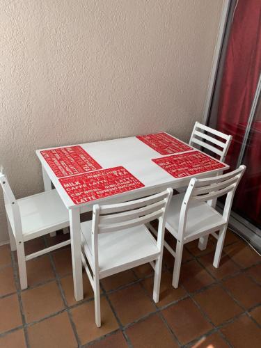une table blanche avec deux chaises et une table et des chaises rouges et blanches dans l'établissement A 35 pas de l'Eau, à Canet