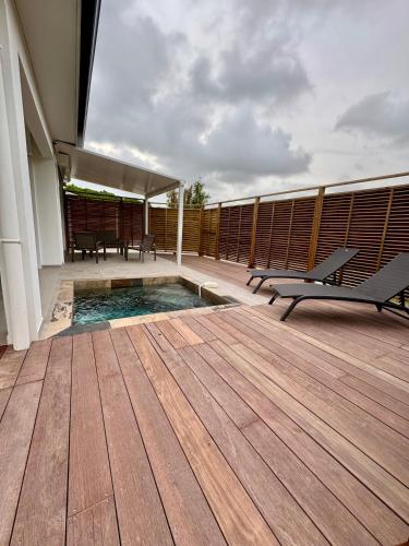 a deck with a pool and benches on a building at Villa Maya & Villa Massaï in Le Marin