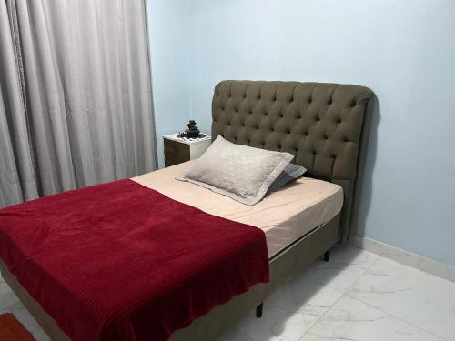 a bed with a large headboard and a red blanket at Apartamento Aconchegante Central (Borboleta) in Itajaí