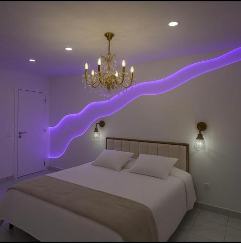 une chambre avec une pièce violette avec un lit et un lustre dans l'établissement TheFloor Hotel - Suite Prestige, à Coignières
