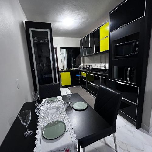 a dining room with a black table and black cabinets at Apartamento Aconchegante Central (Borboleta) in Itajaí