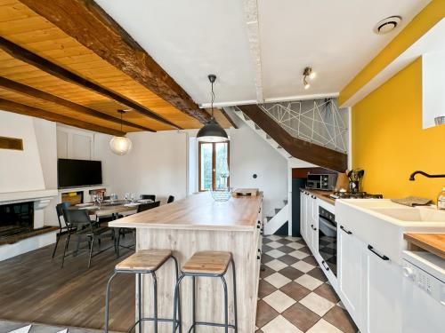 une cuisine avec des murs jaunes et un comptoir avec des tabourets dans l'établissement L'Evasion - Villa Proche Rennes - Calme - Jardin, à Vern-sur-Seiche