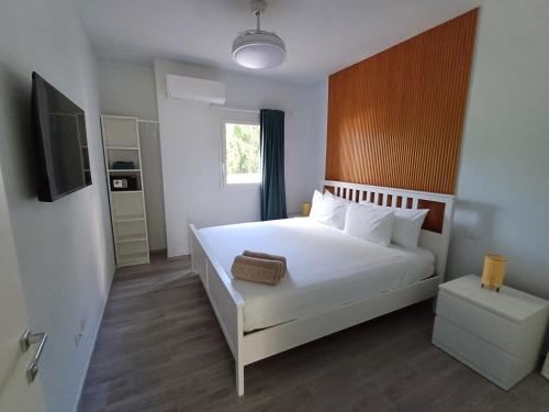 una camera da letto con un grande letto bianco e una televisione di TRACADERO Beach Club & Holidays Rentals a Bayahibe