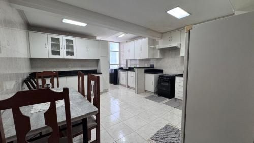 a kitchen with white cabinets and a table and chairs at Confortável apartamento in Jataí