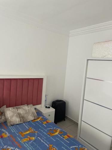 a bedroom with a bed with a red headboard at Tres belle Appartement situee a martil in Martil