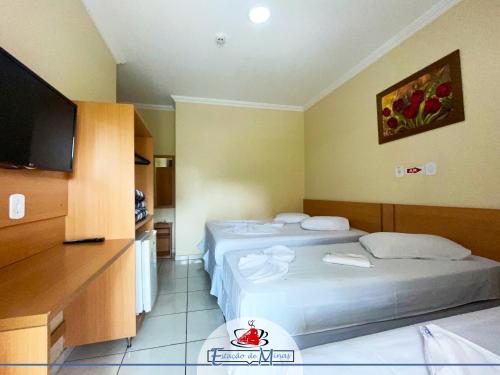 a hotel room with two beds and a flat screen tv at Hotel Estação de Minas in Aparecida
