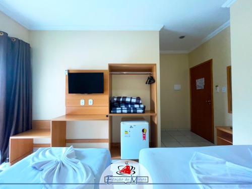a room with a bed and a refrigerator in it at Hotel Estação de Minas in Aparecida
