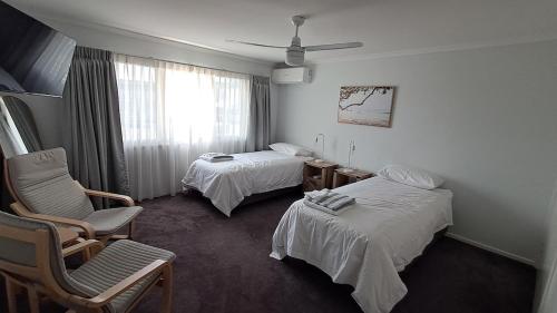 a hotel room with two beds and a chair at Wynnum Creek Retreat in Brisbane