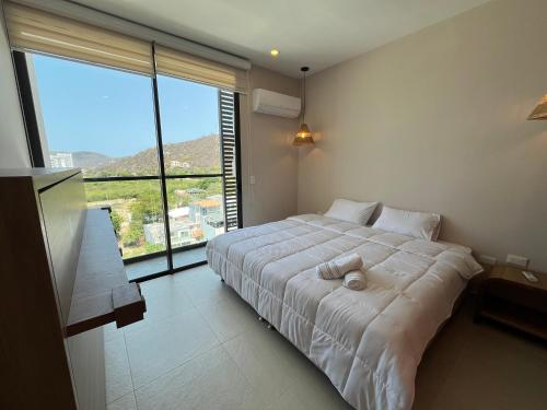 a bedroom with a large bed with a large window at Edificio Salinas del Mar - Pozos Colorados in Santa Marta